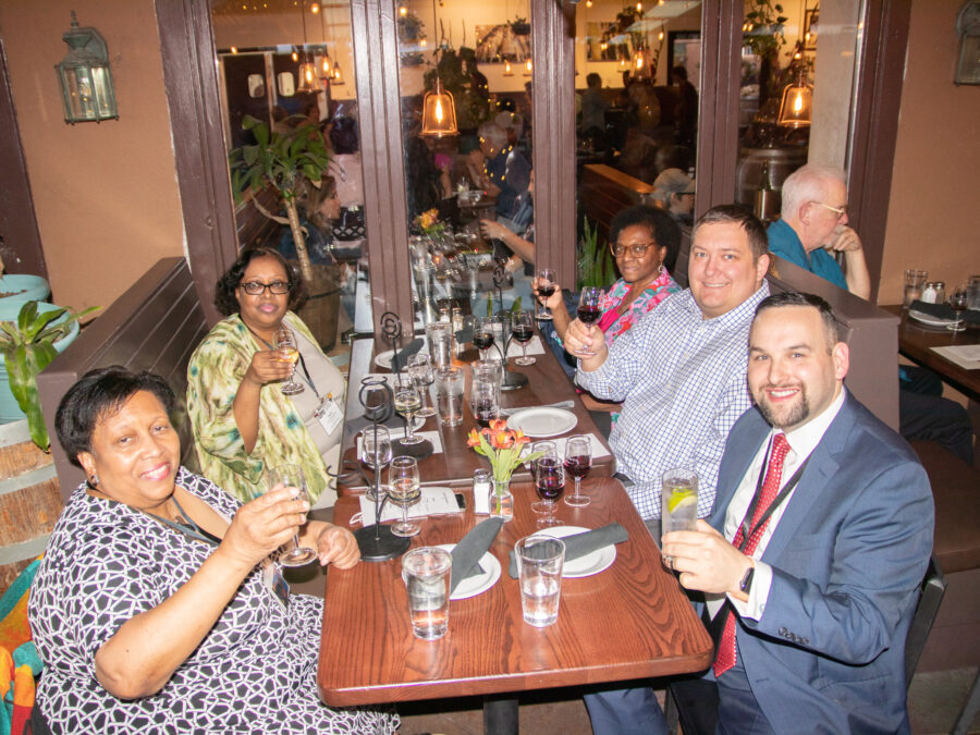 Image: a group holding wine glasses at a restaurant table