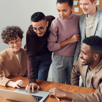 Image: 5 people gathered around a laptop, looking at the screen